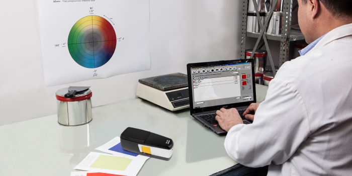 A professional with a white coat in a lab using his laptop for offset printing ink formulation.